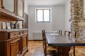 Ein Essbereich mit einem langen Holztisch, Stühlen, einer Steinwand und einem Fenster.