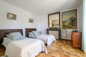 A bedroom with two beds, a fireplace, and artwork on the walls. - Country House "Maison Bourgues" with Cliff View, Wi-Fi, and Air Conditioning (Lioux)