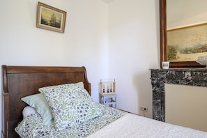 Une chambre à coucher avec un lit en bois, une petite table de chevet avec une lampe et un tableau accroché au mur.