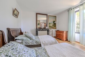 A bedroom with a bed, dresser, mirror, and a view of the outdoors.