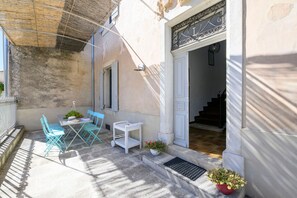 Un patio con una mesa y sillas, una planta colgante y una escalera que conduce a un piso superior.