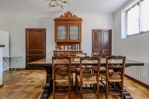 Une salle à manger avec une table en bois, des chaises, un buffet et une fenêtre.