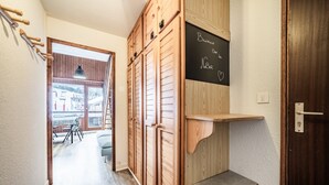 Ein Flur mit Holfachschränken, einer Tafel mit den Aufschriften 'Bienvenue' und 'No Bar' sowie einer Tür mit Schlüsselloch.