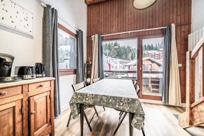 Un coin repas comprenant une table, des chaises, un buffet en bois et une vue sur une station de ski.