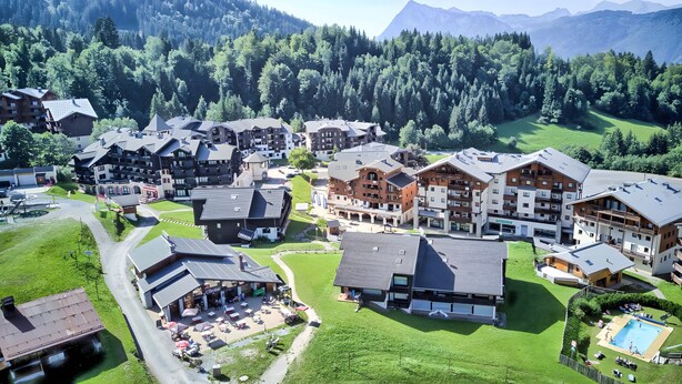 Ein Resort mit mehreren Gebäuden, einem Schwimmbad und einer Bergkulisse.