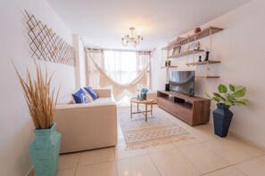 Una sala de estar moderna con sofá, mueble para televisión y plantas decorativas.