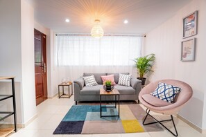 Una sala de estar moderna con un sofá gris, un sillón redondo, una mesa de centro y una alfombra colorida.