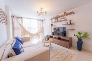 Una sala de estar moderna con un sofá, televisor, estanterías de madera y una planta.
