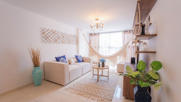 A modern living room with a sofa, a coffee table, and a large window with a view. - Mostaza Ilofts (Medellín)