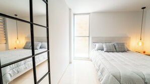 A modern bedroom with a large window, a bunk bed, and a single bed with a headboard. - Mostaza Ilofts (Medellín)