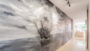 A hallway with a mural of a sailing ship on the wall. - Mostaza Ilofts (Medellín)