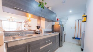 A modern kitchen with a granite countertop, stainless steel appliances, and a built-in oven. - Mostaza Ilofts (Medellín)