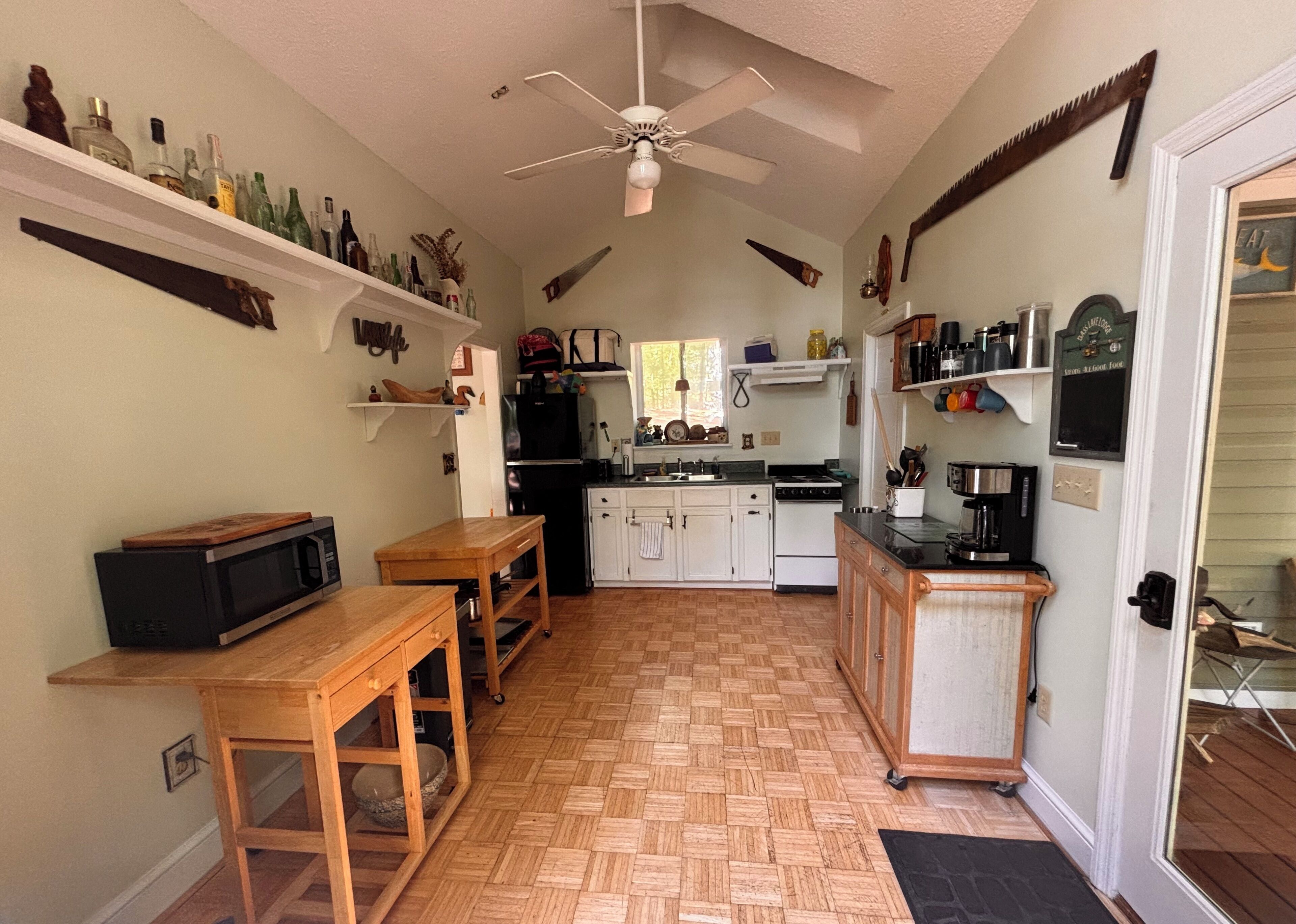 Cozinha compacta com micro-ondas, mesa de madeira e ventoinha no teto.