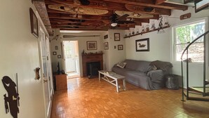 Un salon chaleureux avec un plancher en bois, un canapé gris, une cheminée et un escalier menant à un niveau supérieur.