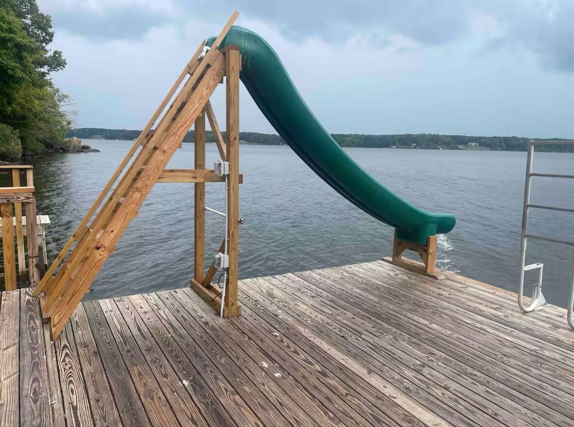 A wooden deck with a green slide extending over a body of water.