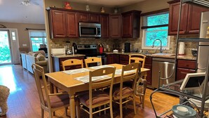 A well-lit kitchen with wooden cabinets, a dining table with chairs, a microwave, stove, and a dishwasher.
