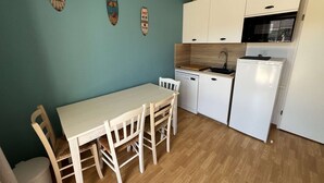 A compact kitchen with a dining table, chairs, a dishwasher, and a refrigerator. - 226 - Comfortable apartment in a residence with swimming pool in Verdon sur Mer (LE VERDON SUR MER)