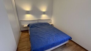 A small, neatly arranged bedroom with a single bed, two wall-mounted lights, and a wooden floor. - 226 - Comfortable apartment in a residence with swimming pool in Verdon sur Mer (LE VERDON SUR MER)