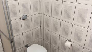 Un baño pequeño con inodoro, ducha y lavamanos.