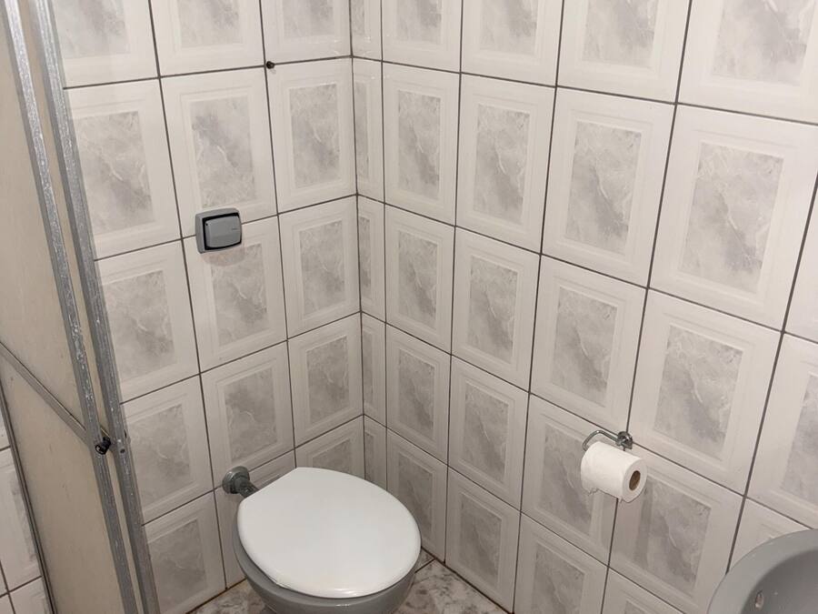 Un baño pequeño con inodoro, ducha y lavamanos.