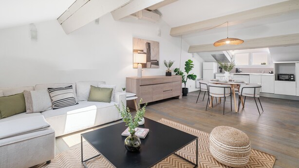 A modern living room with a sofa, coffee table, and dining area.