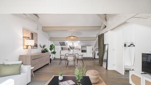 A modern living room with a black coffee table, a white sofa, and a television on a white cabinet.