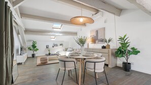 A modern dining area with a round table, four chairs, and a hanging light fixture.