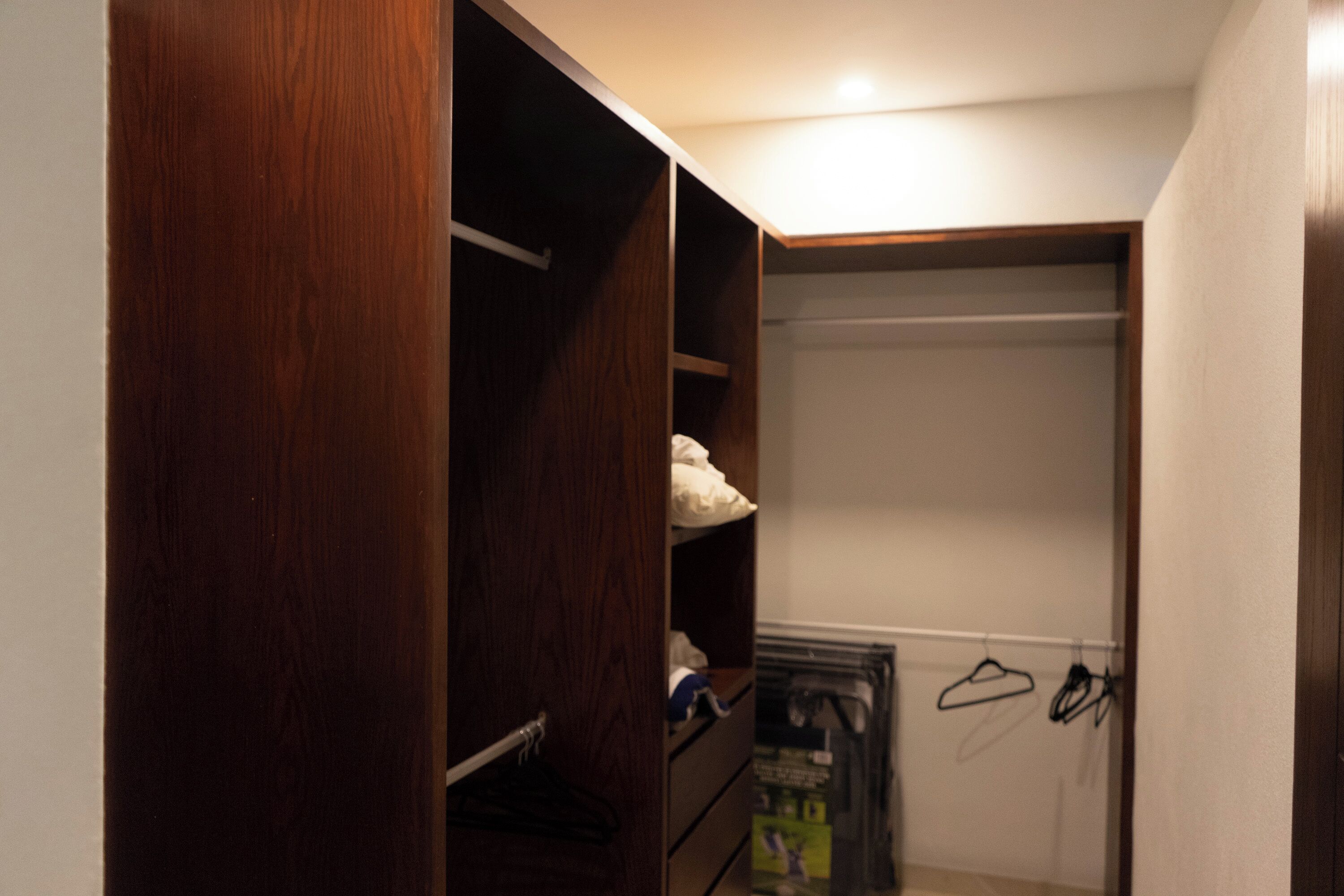 Un dressing avec des portes en bois, des étagères et un espace pour suspendre les vêtements.