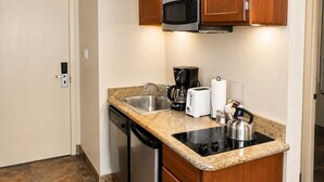 Una cocina compacta equipada con microondas, cafetera, tostadora y hervidor.