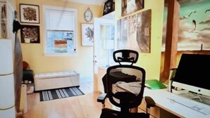 A home office with a desk, computer, and office chair. There is a window with blinds, a door, and a wall with framed pictures. - CHARMING APARTMENT WITH SEPARATE ENTRANCE (southampton)