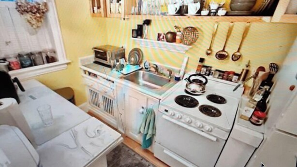 A kitchen with a stove, sink, and various utensils.