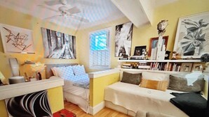 A compact living space with a kitchenette, a sofa, a small table, and a bookshelf.