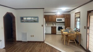 A kitchen with wooden cabinets, a microwave, and a dining table with chairs. - Charming 2-bedroom condo with WiFi, AC in fantastic North Ocean City (Ocean City)