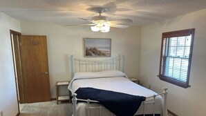 A bedroom with a single bed, a ceiling fan, a nightstand, a window with blinds, and a door. - Charming 2-bedroom condo with WiFi, AC in fantastic North Ocean City (Ocean City)
