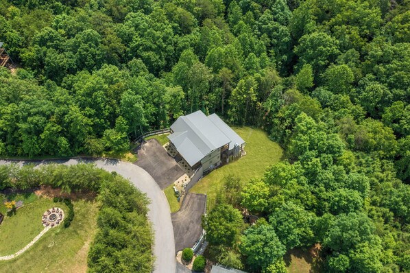 An aerial view of a property with a large building surrounded by dense forest.