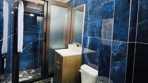A modern bathroom with a glass shower enclosure, a wooden vanity, and a marble-tiled wall. - hostal bode de lago rooms  #3 (Panajachel)