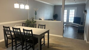 Un coin repas avec une table et des chaises, un luminaire suspendu et une plante.