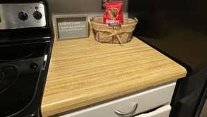 Une cuisine avec un plan de travail en bois, une cuisinière, un réfrigérateur et un paquet de café posé sur le plan de travail.