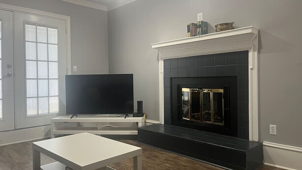 Un salon avec une cheminée, un téléviseur à écran plat et une table blanche.