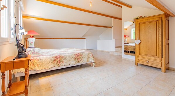 Un dormitorio con una cama, un armario de madera y un escritorio con una lámpara.
