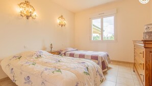 A bedroom with two beds, a nightstand, a dresser, and a window with a view. - Les Portes Roses - VARENNE SAINT GERMAIN (VARENNE SAINT GERMAIN)