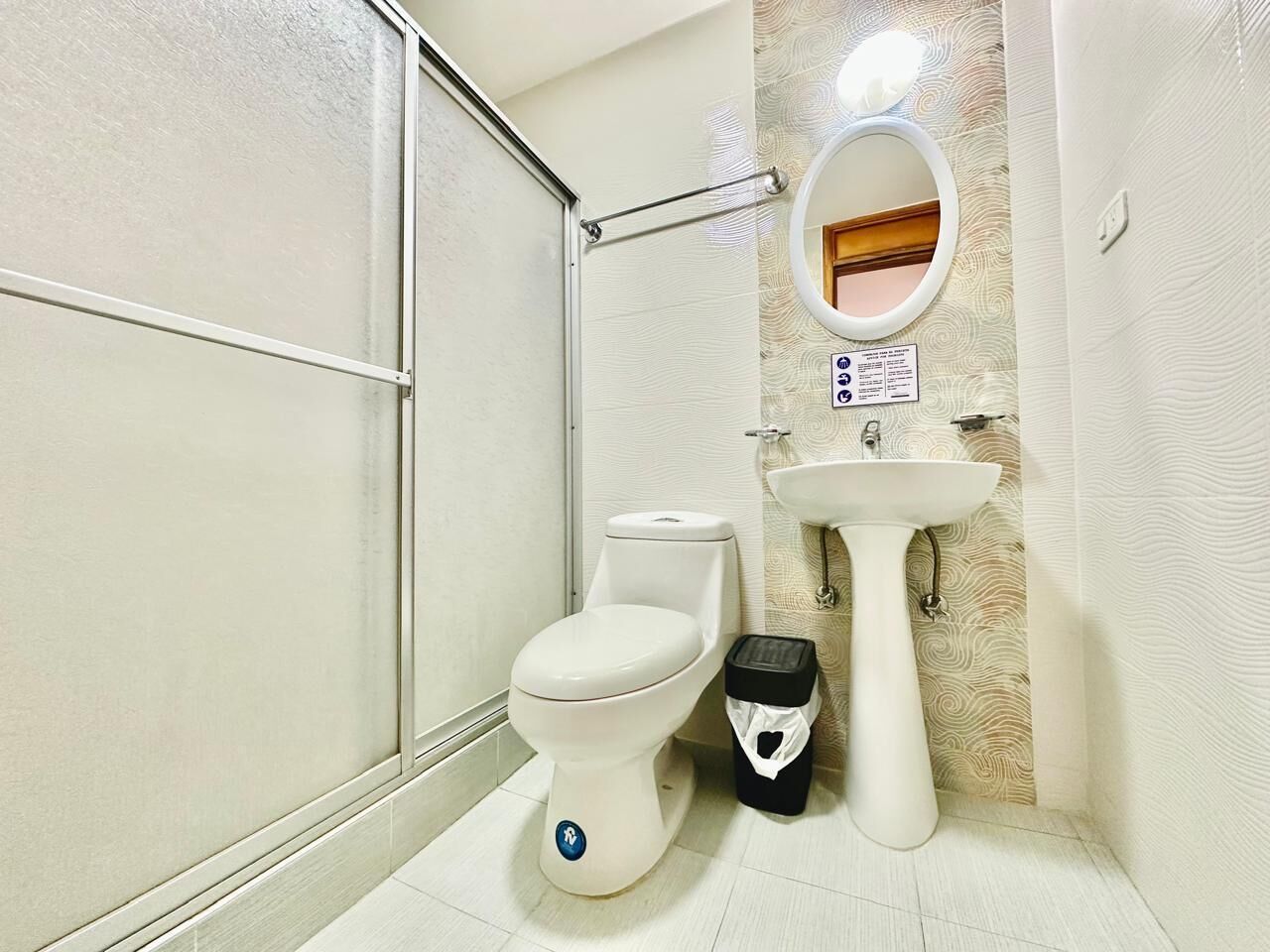 Un baño con inodoro, lavamanos y un cesto de basura.