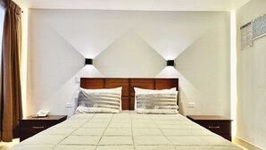 A hotel room with a large bed, two bedside tables, a telephone, and a wall-mounted light fixture. - Hotel Tiwintza Internacional (Quito)