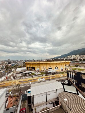 A view of a cityscape with a prominent yellow building with arches, surrounded by other buildings and a cloudy sky. - Hotel Tiwintza Internacional (Quito)