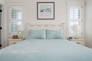 A bedroom with a bed, two nightstands, a framed picture on the wall, and windows with blinds. - Between the Cs: Soundside, Private Pool, Elevator (Kitty Hawk)