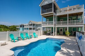 A two-story house with a swimming pool, outdoor seating, and a fenced yard.