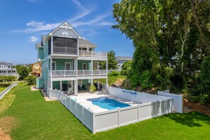 Ein zweigeschossiges Haus mit einem Balkon und einem Swimmingpool.