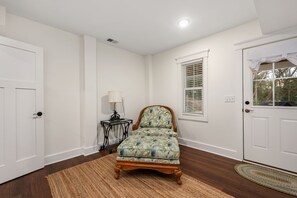 A bedroom with a single bed, a nightstand, a lamp, a window with blinds, and a door. - Between the Cs: Soundside, Private Pool, Elevator (Kitty Hawk)