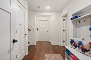 A hallway with white doors, a wooden floor, and a bench with colorful pillows. - Between the Cs: Soundside, Private Pool, Elevator (Kitty Hawk)