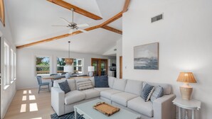 A spacious living room with a large sectional sofa, a coffee table, and a dining area with a table and chairs.